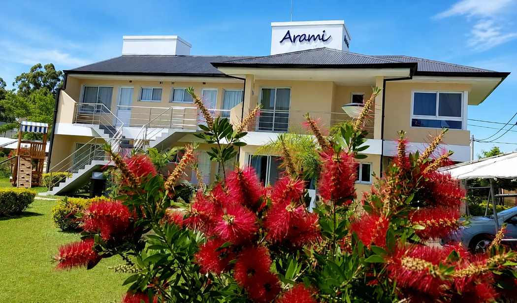 Complejo Arami Apart exterior framed by red flowers